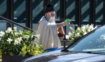 El padre de una iglesia usó una pistola de agua bendita para bendecir a sus fieles