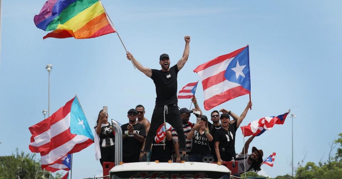 Ricky Martín ondeando la bandera del orgullo LGBTTTIQ+ en la masvia marcha contra Roselló.